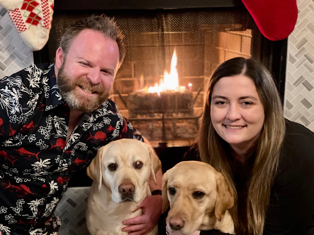 Couple with dogs in front of a fireplace