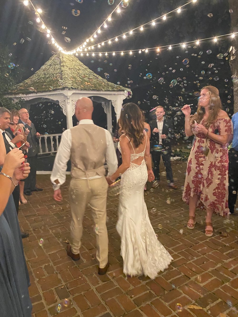 Wedding couple leaving with guests blowing bubbles