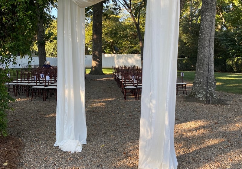 White cloth draped over a large bough with chairs in rows